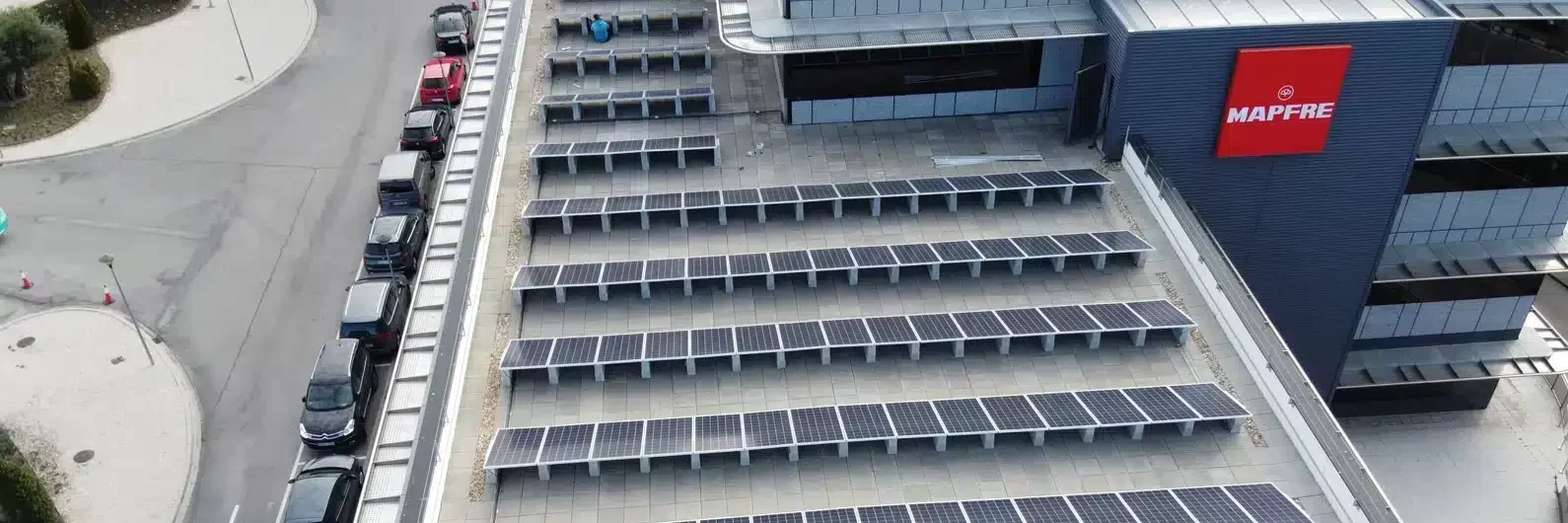 articulo Funcionários da MAPFRE junto a veículos elétricos, simbolizando o compromisso com a Pegada de Carbono 2025.