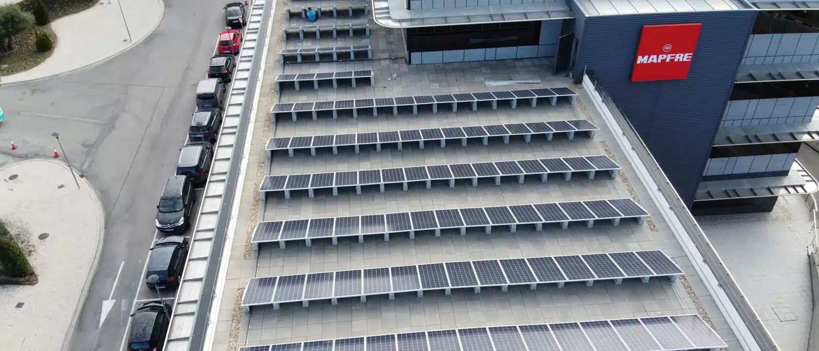 articulo Funcionários da MAPFRE junto a veículos elétricos, simbolizando o compromisso com a Pegada de Carbono 2025.